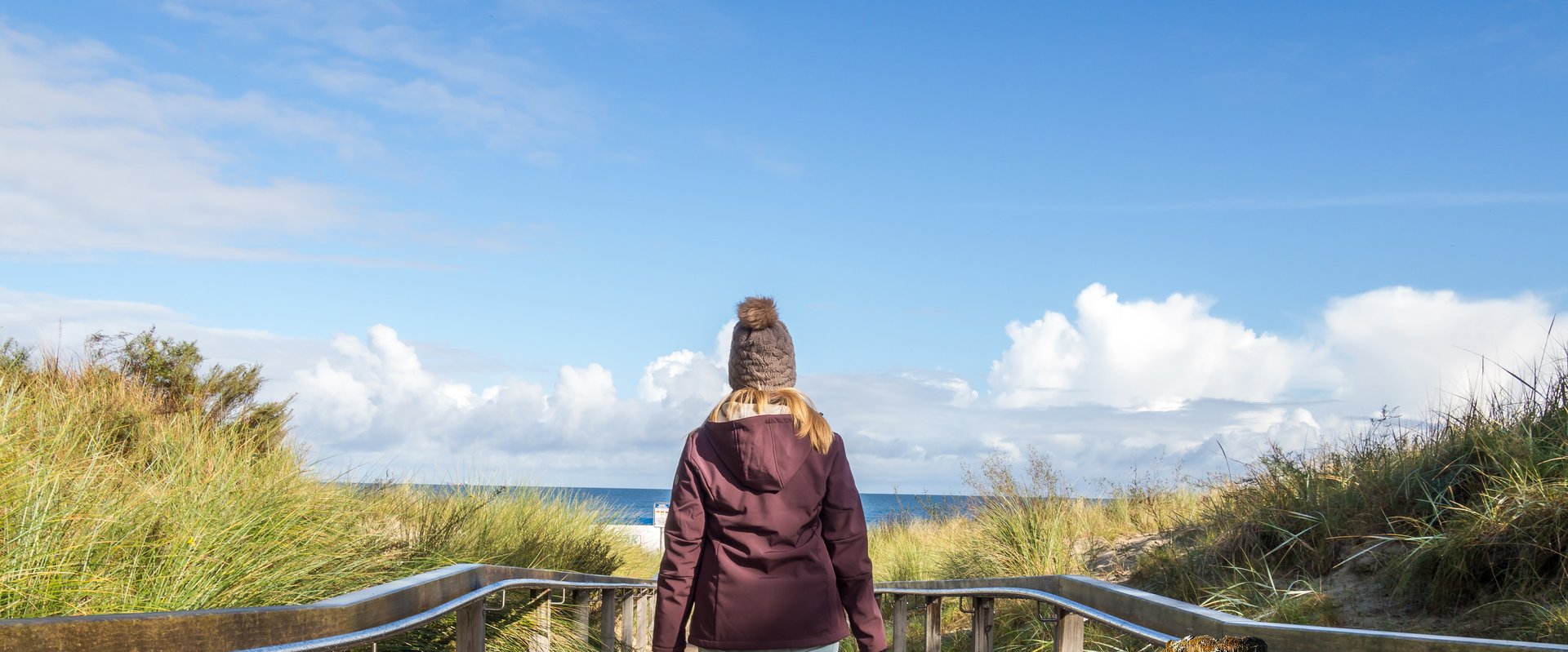Mädchen von hinten auf einer Düne am Meer. Foto: Animaflora/AdobeStock