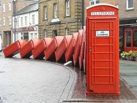 Skulptur „Out of Order“ von David Mach in Kingston upon Thames, eine Reihe rot lackierte Telefonzellen, die wie Dominosteine ineinander fallen. Foto: Kingston upon Thames