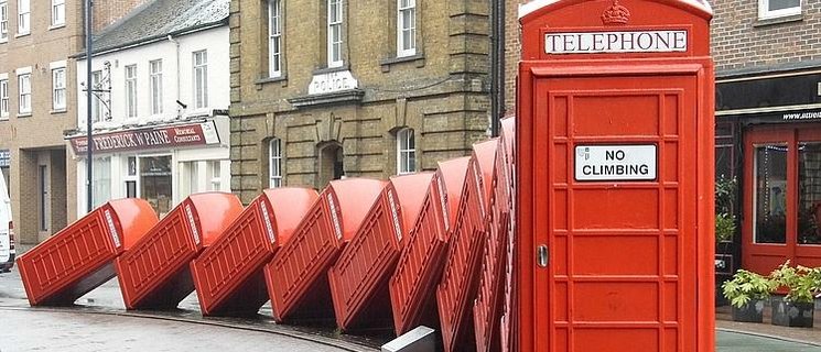 Skulptur „Out of Order“ von David Mach in Kingston upon Thames, eine Reihe rot lackierte Telefonzellen, die wie Dominosteine ineinander fallen. Foto: Kingston upon Thames