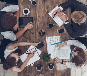 Mehrere Menschen sitzen um einen Besprechungstisch herum. Foto: Dima Sidelnikov/Fotolia
