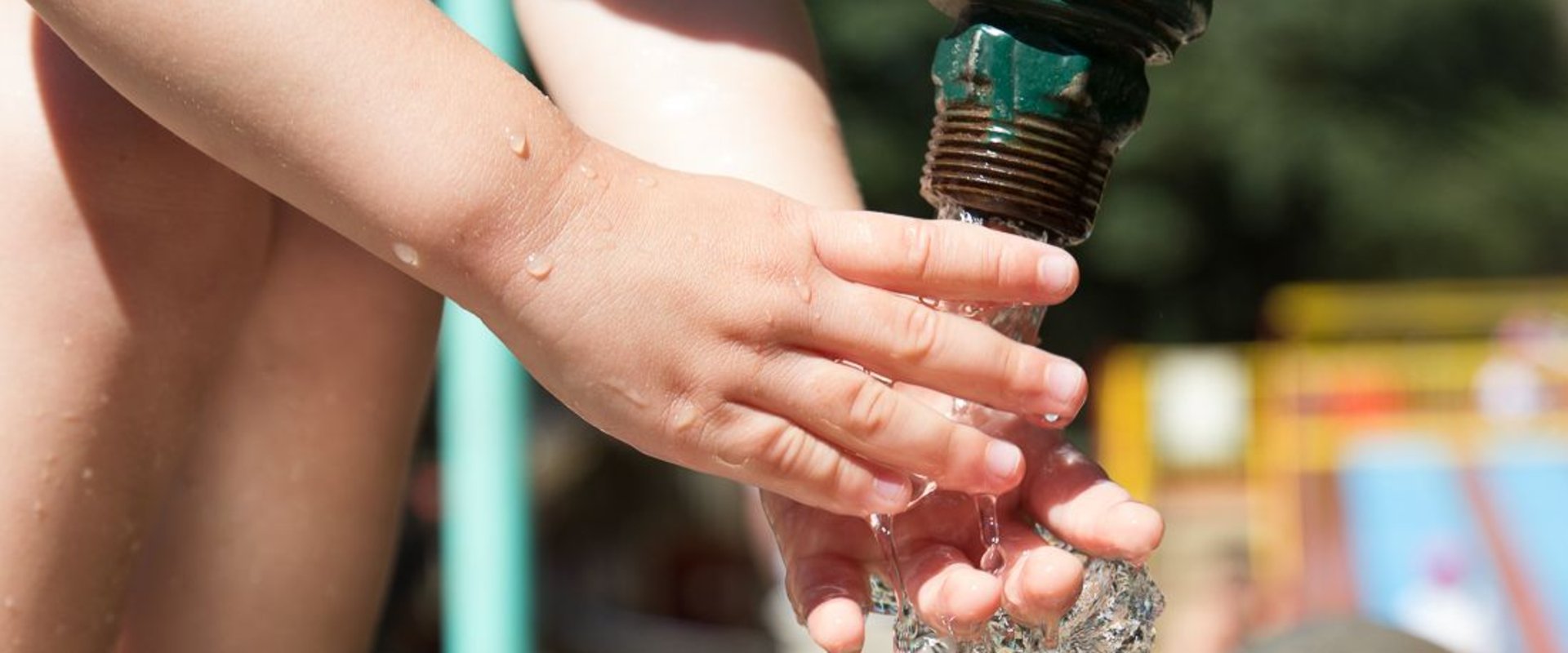 Kinderhand im Wasserstrahl. Foto: Charlie Baer/pixelio.de