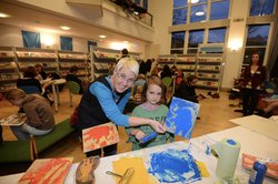 Eine Frau und ein Mädchen zeigen ein gemaltes Bild. Foto: Buchkinder Oldenburg