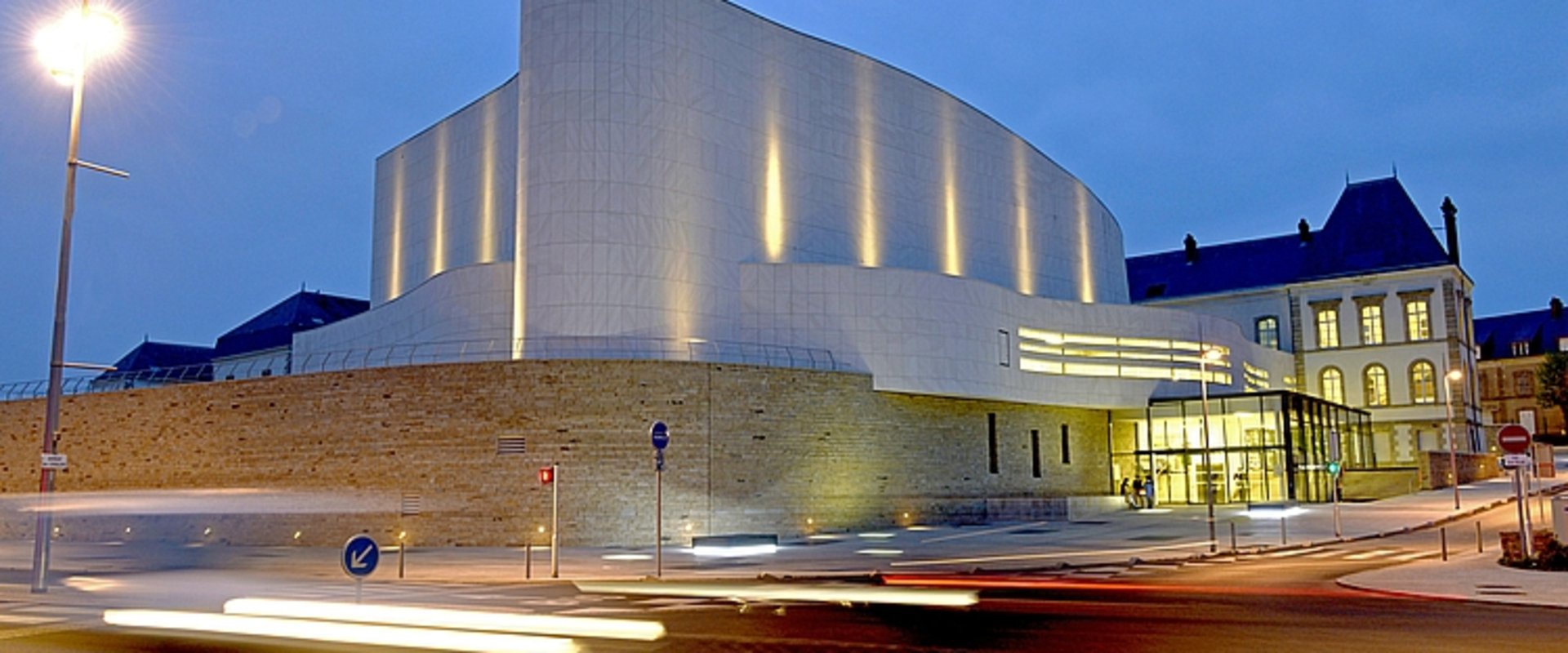 Théâtre Saint-Louis in Cholet bei Nacht, ein weißes, modernes Gebäude mit geschwungener Form. Foto: Mathilde Richard