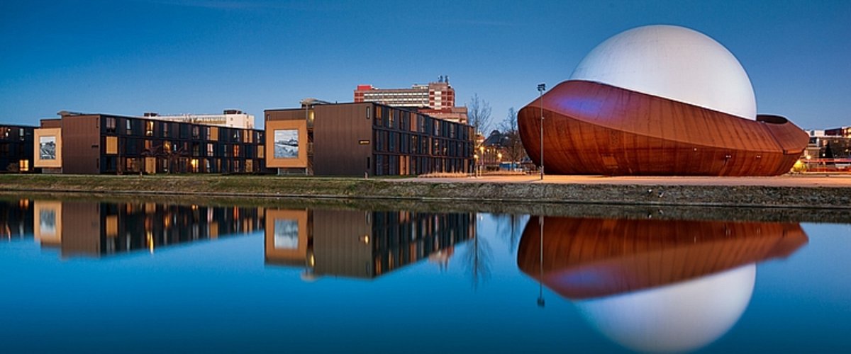 Eine moderne Gebäudereihe spiegelt sich in einem stillen Gewässer. Foto: Marketing Groningen