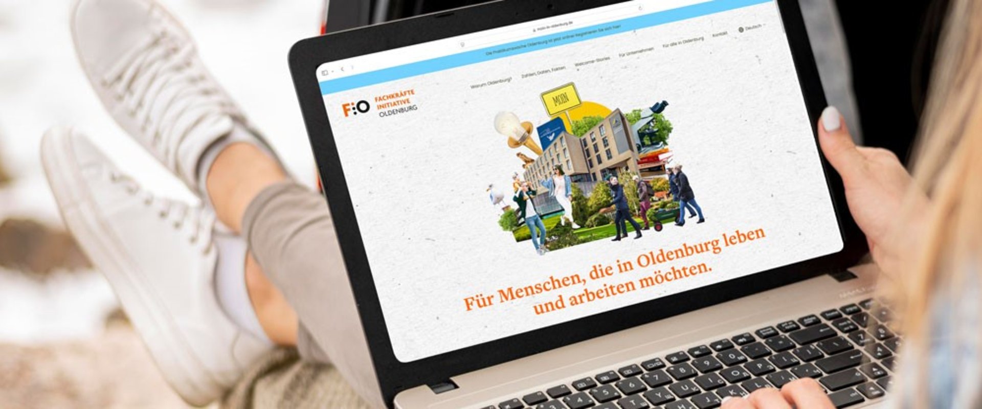 Junge Frau mit Laptop auf den Beinen surft auf der Homepage von „Moin in Oldenburg“. Foto: Superidee
