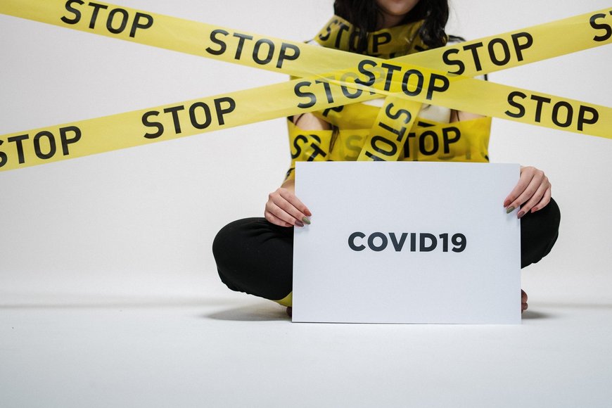 Frau eingewickelt in gelben Stop-Flatterbändern mit Corona-Schild. Foto: cottonbro/Pexels.com