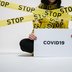 Vorschau: Frau eingewickelt in gelben Stop-Flatterbändern mit Corona-Schild. Foto: cottonbro/Pexels.com