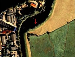 Luftbild vor den Ausgrabungsarbeiten: Der Ringwall zeichnet sich durch einen dunkleren Halbkreis ab. Quelle: Niedersächsisches Ministerium für Wissenschaft und Kultur