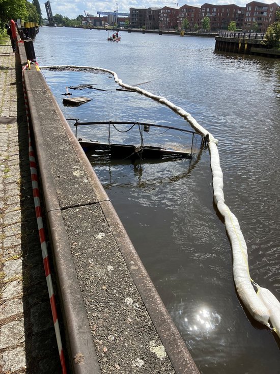 Nachdem der Katamaran im Oldenburger Hafen abgebrannt ist, ist das Boot zwei Tage später gesunken. Zu sehen ist nur noch die Ölsperre der Feuerwehr. Foto: Stadt Oldenburg Foto: Stadt Oldenburg