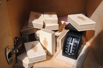 Holzklötze mit Mann- und Frauabbildung neben kleiner Waage. Foto: Stadt Oldenburg