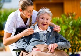 Pflegerin hält die Hand einer Seniorin im Rollstuhl. Foto: Kzenon/Fotolia.com