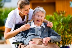 Pflegerin hält die Hand einer Seniorin im Rollstuhl. Foto: Kzenon/Fotolia.com