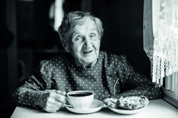 Alte Dame am Tisch sitzend mit Kaffeetasse. Foto: De Visu/Fotolia.com
