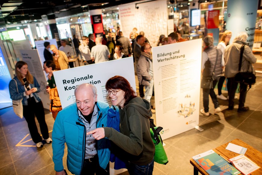 Zwei strahlende Menschen vor einer Infotafel. Foto: Hauke-Christian Dittrich