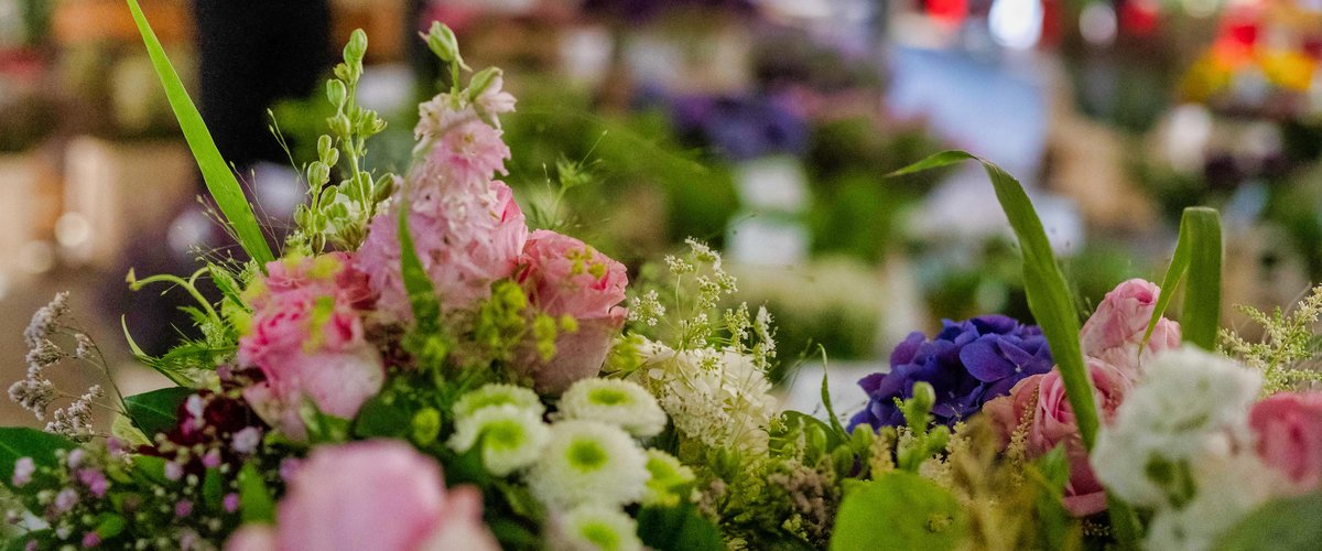 Blumensträuße mit Marktgeschehen im Hintergrund. Foto: Sascha Stüber
