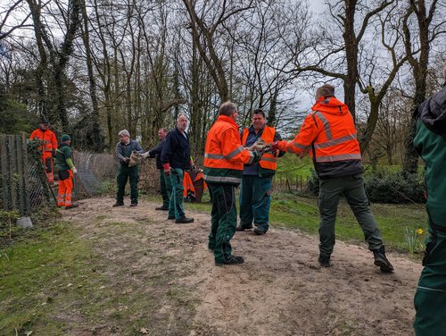 Mitarbeitende des Grünflächenamtes räumen per Menschenkette Sandsäcke aus unbefahrbarem Gelände in der Nähe des Friedhofs. Foto: Stadt Oldenburg