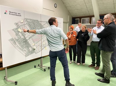 Bürgerinnen und Bürger an einer Informationstafel Foto: CapitalReal GmbH & Co. KG Bürgerinnen und Bürger an einer Informationstafel