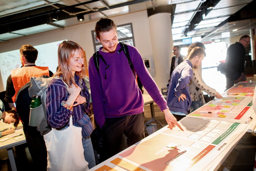 Zwei junge Menschen stehen interessiert bei dem Themenfeld Wirtschaft. Foto: Hauke-Christian Dittrich