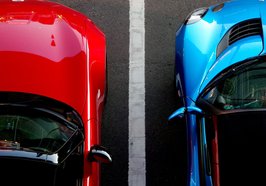 Aufnahme aus der Vogelpersepktive von zwei parkenden Autos in rot und blau. Foto: Possesed Photography/unsplash