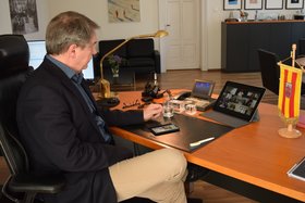 Oberbürgermeister Jürgen Krogmann sitzt an seinem Schreibtisch. Auf einem Laptop-Bildschirm vor ihm sind die Bilder weiterer an der Videokonferenz beteiligter Personen zu sehen. Foto: Stadt Oldenburg