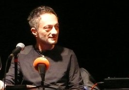 Feridun Zaimoglu sitzt vor einem Mikrofon. Foto: Literaturhaus Oldenburg