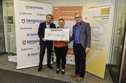 Christian Bunk, Vertriebsdirektor Öffentliche Versicherungen Oldenburg, überreichte den Scheck an Uwe Schumacher, Geschäftsführer, und Katharina Tchuente Sime, Assistentin der Geschäftsführung der Jugend- und Familienhilfe Oldenburg. Foto: Uwe Schuc Christian Bunk, Vertriebsdirektor Öffentliche Versicherungen Oldenburg, überreichte den Scheck für das Erreichen des sechsten Etappenziels an Uwe Schumacher, Geschäftsführer, und Katharina Tchuente Sime, Assistentin der Geschäftsführung der Jugend- und Familienhilfe Oldenburg gGmbH. Foto: Uwe Schucht, Öffentliche Versicherungen Oldenburg.