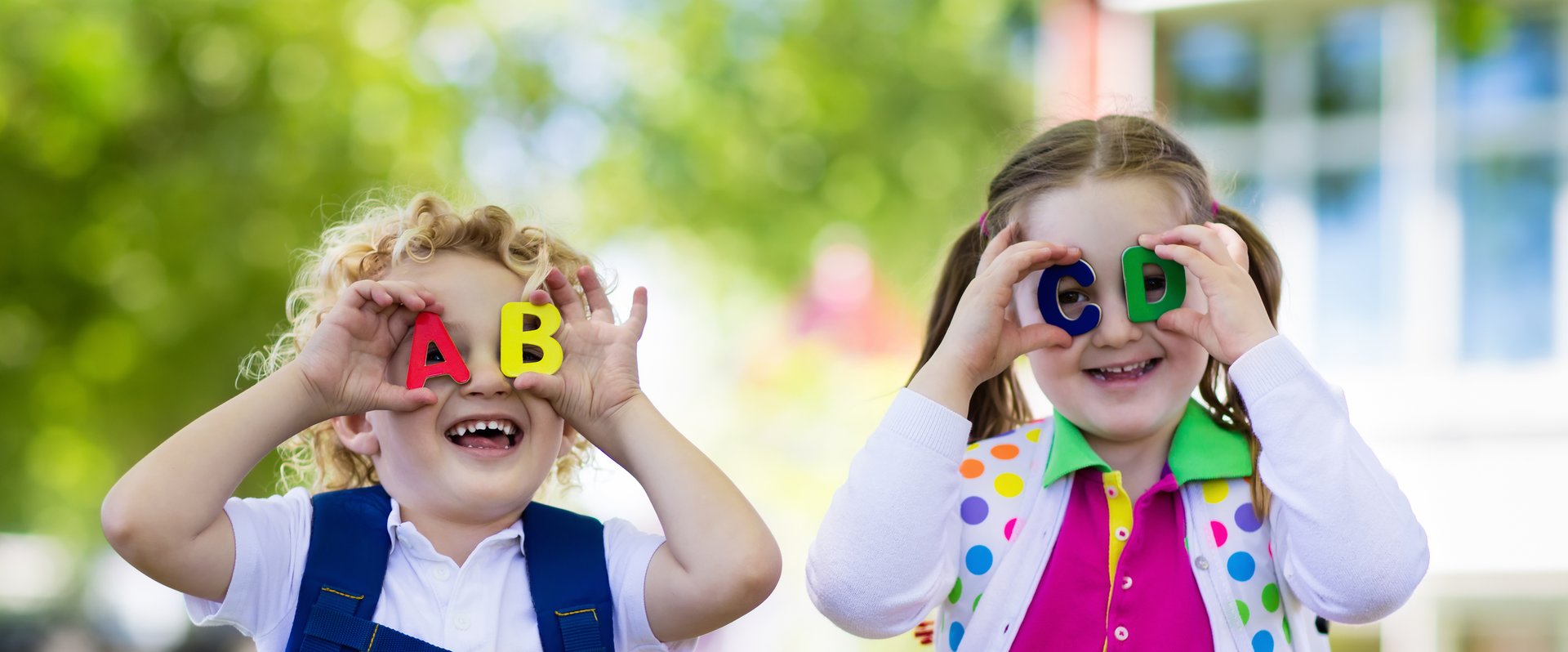 Zwei Kinder halten sich Buchstaben aus Kunststoff vor die Augen. Foto: famveldman/AdobeStock
