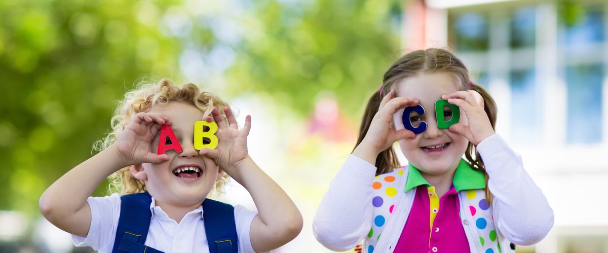 Zwei Kinder halten sich Buchstaben aus Kunststoff vor die Augen. Foto: famveldman/AdobeStock