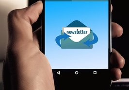 Linke Hand hält Smartphone mit Symbol für Newsletter: geöffneter Briefumschlag mit Dokument mit Aufschrift „Newsletter“ sowie Pfeilen zur Verdeutlichung von Ein- und Ausgang. Foto: Gerd Altmann/Pixabay