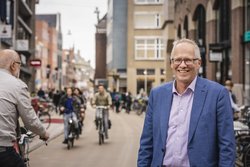 Stadtrat Philip Broeksma. Foto: Jeroen van Kooten Stadtrat Philip Broeksma im Vordergrund einer Straße mit vielen Fahrradfahrenden in Groningen. Foto: Jeroen van Kooten