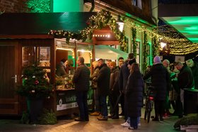 Menschen stehen an der Holzhütte für Grünkohleintopf an. Foto: OTM/Henricus Lüschen