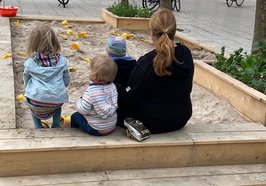Mutter mit drei Kindern im Kinderstadtgarten, von hinten fotografiert. Foto: Stadt Oldenburg