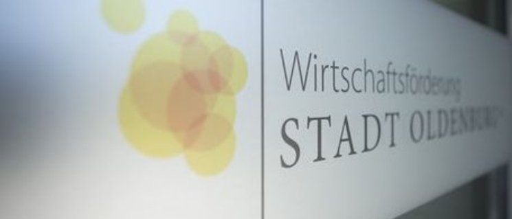Logo Wirtschaftsförderung Stadt Oldenburg auf Eingangstür. Orangefarbene, sich überschneidende Bubbles mit Schriftzug. Foto: Markus Monecke, Studio M