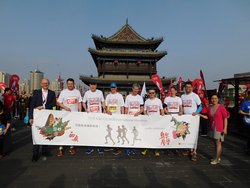Die Oldenburger Laufdelegation in Xi'an. Foto: Stadt Oldenburg Die Oldenburger Laufdelegation steht vor einer Pagode. In der Hand ein Banner mit Motiven aus Oldenburg und Xi'an und der Aufschrift „Laufen verbindet“. Foto: Stadt Oldenburg