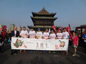 Die Oldenburger Laufdelegation steht vor einer Pagode. In der Hand ein Banner mit Motiven aus Oldenburg und Xi'an und der Aufschrift „Laufen verbindet“. Foto: Stadt Oldenburg