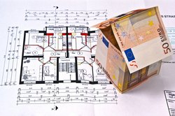 Ein Haus aus Geldscheinen steht auf einem Bauplan. Foto: Grabscheit/Pixelio.de