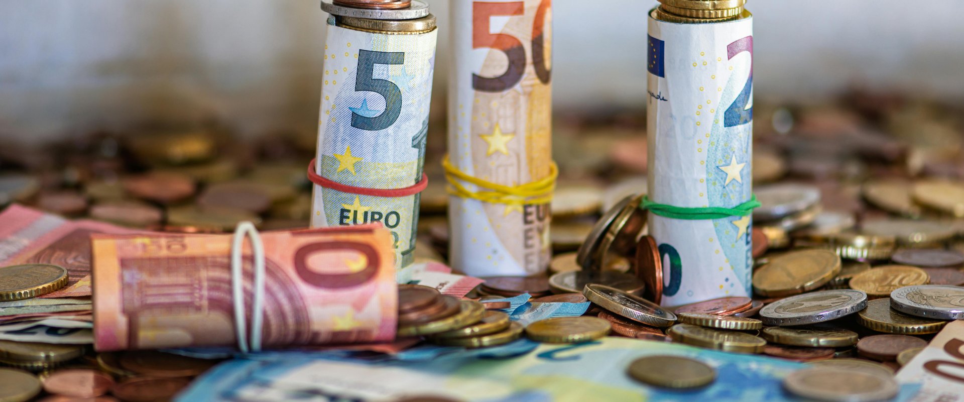 Gerollte Euro-Banknoten und Münzen auf einem Tisch. Foto: Willfried Wende/Pexelse