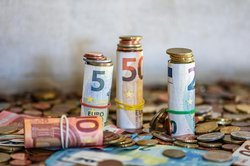 Gerollte Euro-Banknoten und Münzen auf einem Tisch. Foto: Willfried Wende/Pexelse