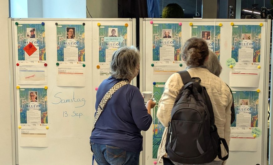 Teilnehmende stehen vor den Listen mit Restplätzen in den Workshops. Foto: Stadt Oldenburg