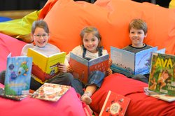 Louisa, Marlena und Maximilian stöbern vor dem Start der KIBUM in einigen Büchern aus dem Gastland Schweiz. Foto: Mohssen Assanimoghaddam