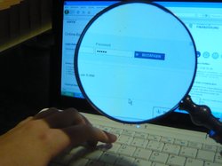 Bildschirm eines Laptops mit Lupe, die die Eingabe eines Passworts zeigt. Foto: Christine Lietz/Pixelio