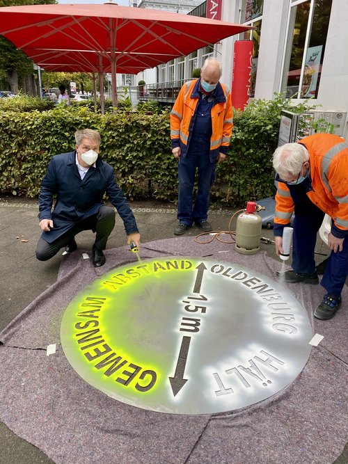 Abstand halten in Corona-Zeiten: Oberbürgermeister Jürgen Krogmann hat heute das erste Piktogramm in der Innenstadt aufgebracht. Unterstützt wurde er von Günter Denker (Mitte) und Peter Laker von der Beschilderungswerkstatt der Stadt. Foto: Stadt Oldenburg