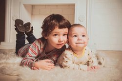Kinder liegen auf einem Teppich. Foto: vika glitter/Pexels.com