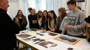 Schülerinnen und Schüler stehen um einen Tisch herum, auf dem verschiedene Stadtansichten liegen. Foto: Anja Czibulinski