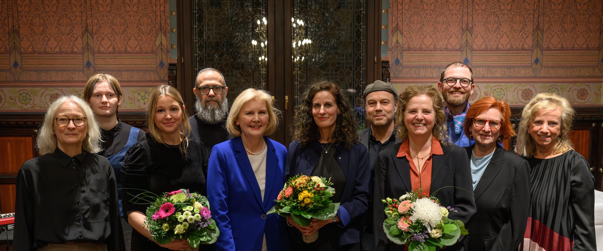 Preisträgerin Eva Kranenburg (Mitte mit Blumen) mit den Mitgliedern der Jury, der Leiterin des Kulturbüros Paula von Sydow (links), Bürgermeisterin Petra Averbeck (fünfte von links) sowie Laudator Vitali Konstantinov (vierter von links) und den weiteren Nominierten Heike Falkenberg (vierte von rechts) und Jenny Hungerbühler (dritte von links). Foto: Mohssen Assanimoghaddam