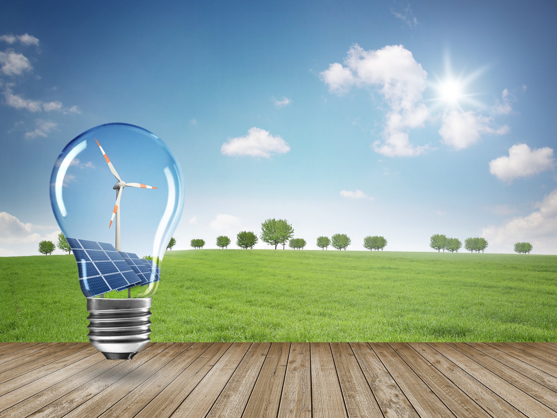 Glühbirne mit Windrad und Solaranlage vor grüner Landschaft. Foto: Coloures-Pic/AdobeStock