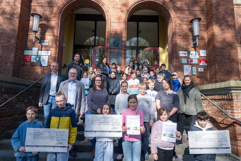 So sehen Siegerinnen und Sieger aus: Schülerinnen und Schüler sowie Lehrkräfte des Herbartgymnasiums Oldenburg, der Freien Schule Oldenburg und der Grundschule Kreyenbrück nahmen von AWB-Leiter Marco Janssen (zweite Reihe von vorne, links) die Schecks für ihr Engagement für „Oldenburg räumt auf“ entgegen. Foto: Sascha Stüber
