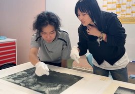 Behutsam mit weißen Handschuhen betrachten Zhenpeng Zhang (links) und Jianing Wang einen Original-Druck von Horst Janssen. Foto: Stadt Oldenburg