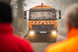 Zwei Mitarbeitende des Abfallwirtschaftsbetriebs Stadt Oldenburg schauen auf ein Reinigungsfahrzeug. Foto: Mohssen Assanimoghaddam