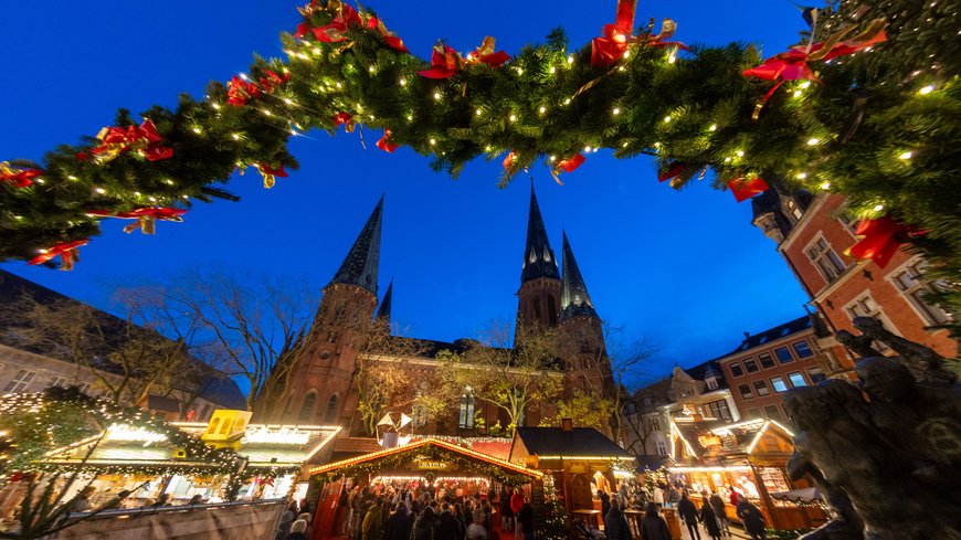 Blick durch einen beleuchteten Bogen in Richtung Lamberti-Kirche beim Lamberti-Markt 2023. Foto: Sascha Stüber